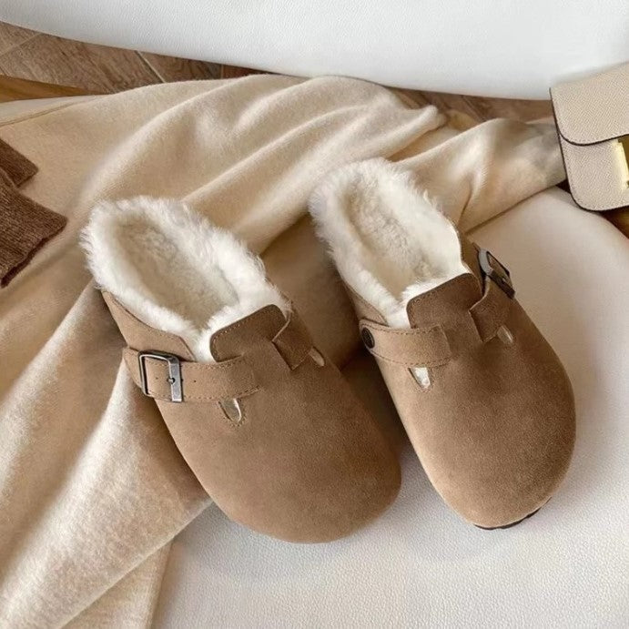 Beige suède sandalen met gesp liggend op een licht kleed